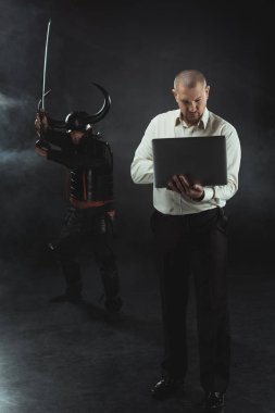 concentrated man using laptop while samurai standing behind him with sword clipart