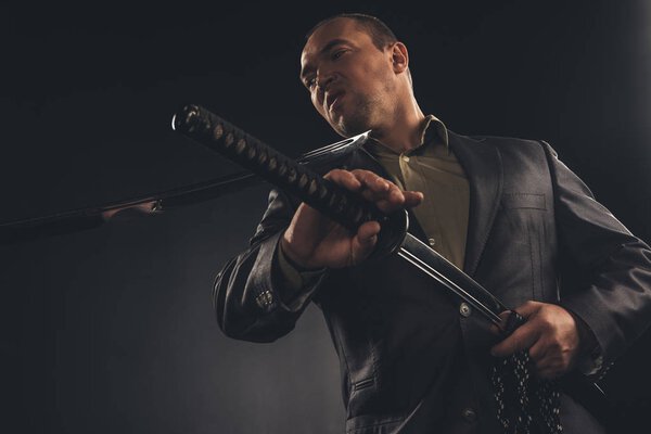 бизнесмен, ковыряющийся с Катаной в шее, вынимая меч, изолированный на черном
