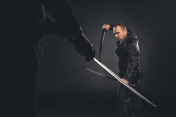 mature modern samurai in suit ready to fight on black