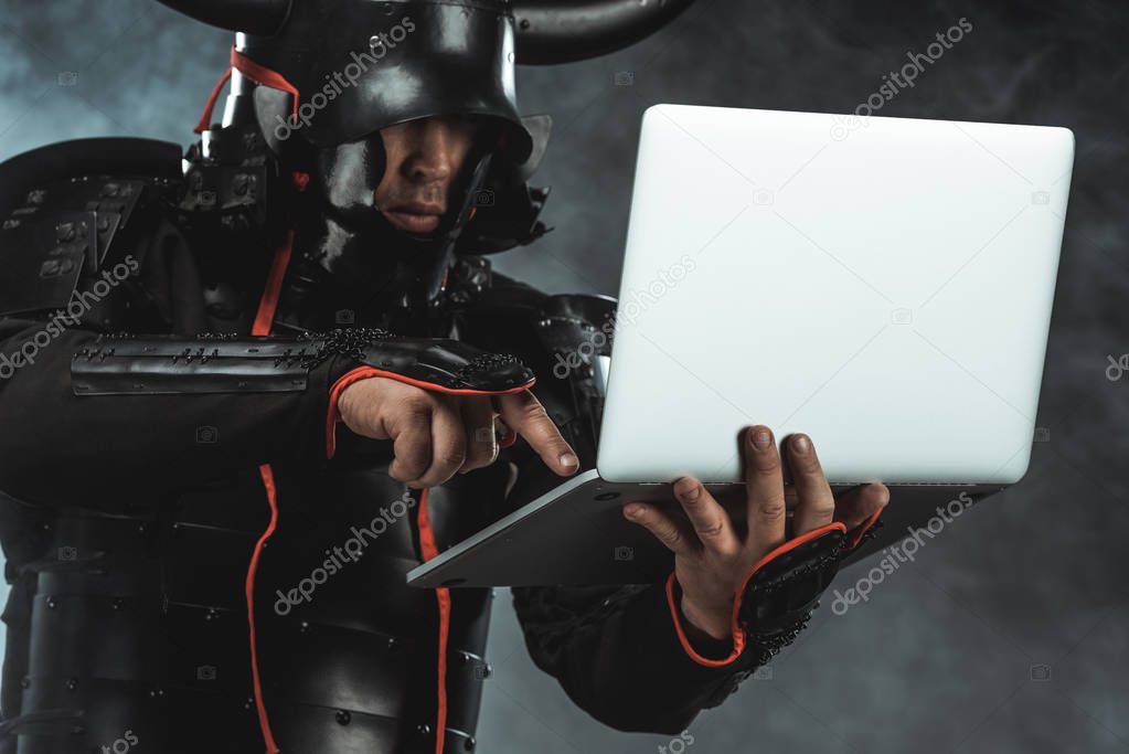 close-up shot of samurai using laptop on dark background with smoke