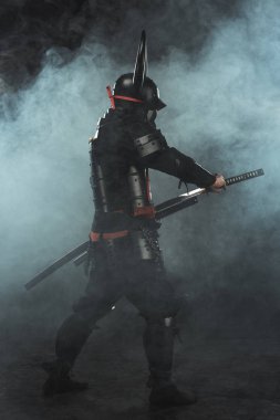 side view of samurai taking out his katana on dark background with smoke clipart