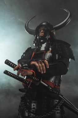duman ile koyu arka plan üzerinde samuray kılıç ile geleneksel zırh alttan görünüm