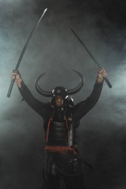 samurai in armor with dual katana swords on dark background with smoke clipart