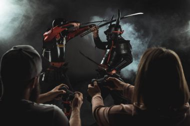 erkek ve kadın gamepads siyah ile gerçek hayatta mücadele samurai oynarken arka görünüm