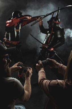 arkadan görünüşü gamepads siyah ile gerçek hayatta mücadele samurai oynayan kadın ve erkek