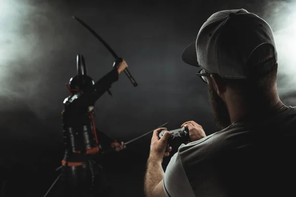 Mann Steuert Samurai Figur Mit Gamepad Auf Schwarz — Stockfoto