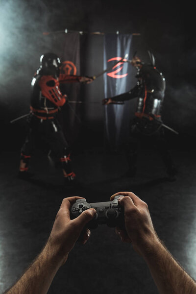 cropped shot of playing samurai fighting with gamepad in real life