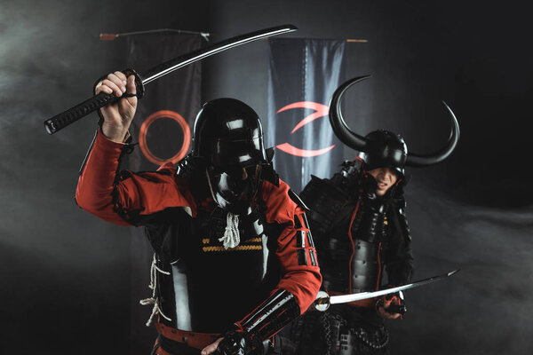 armored samurai fighting with katana swords in front of clan symbols on flags