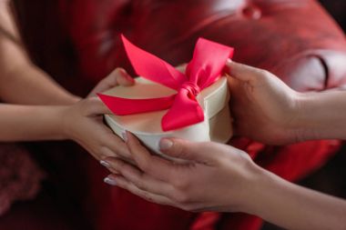 cropped shot of mother giving present in shape of heart to daughter clipart