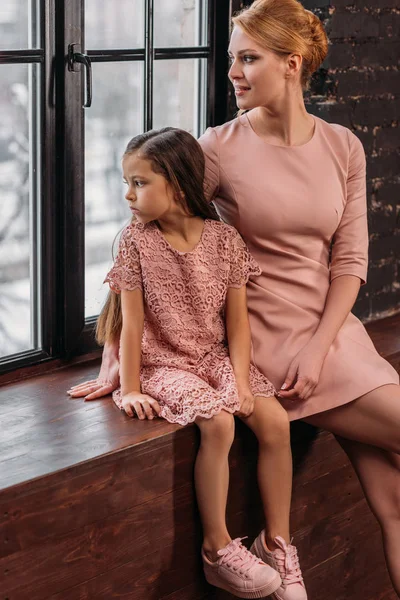 Mutter Und Tochter Sitzen Auf Fensterbank Und Blicken Auf Fenster — kostenloses Stockfoto