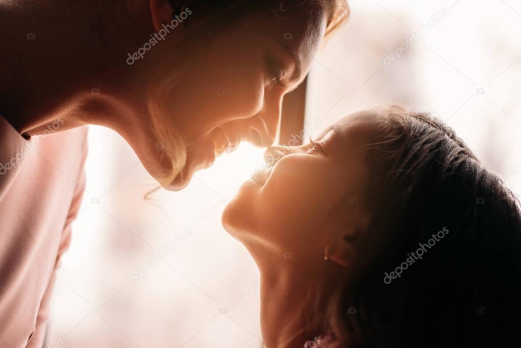 close-up shot of mother and daughter cuddling on sunshine background