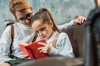 genç anne ve kızı okuma kitabı birlikte kanepede