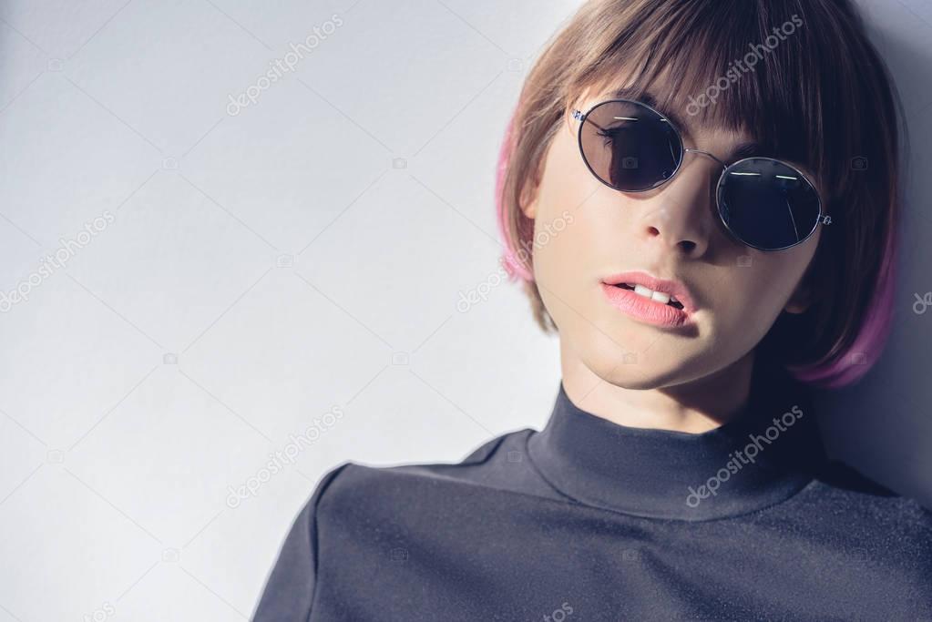 portrait of fashionable girl with pink hair and sunglasses on white