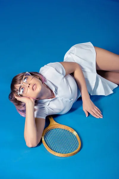 诱人的女子网球运动员躺在网球拍和寻找蓝色 — 免费的图库照片