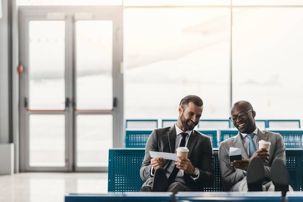 happy business colleagues waiting for flight in airport lobby 