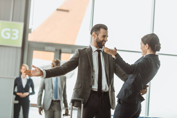 happy businessman embracing colleague at airport