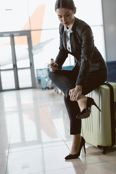 бизнесмен с болью в лодыжке в ожидании рейса в вестибюле аэропорта
