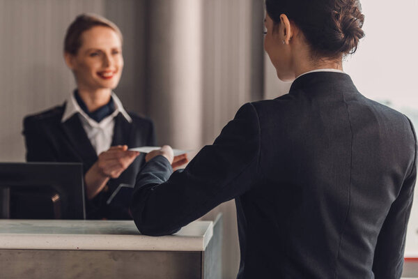 rear view of businesswoman giving ticket to staff at airport check in counter