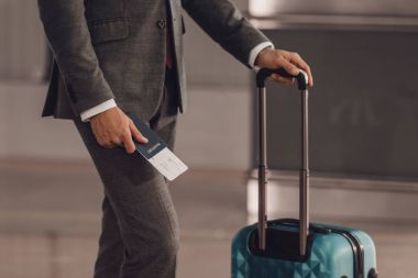 cropped shot of businessman with luggage and flight ticket at airport clipart