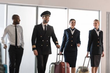 happy aviation personnel team walking by airport loggy with suitcases clipart