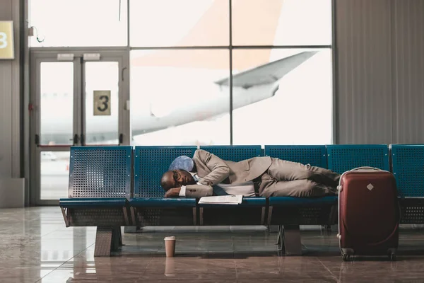 疲惫的商人在机场大堂等候航班时睡在座位上 — 图库照片