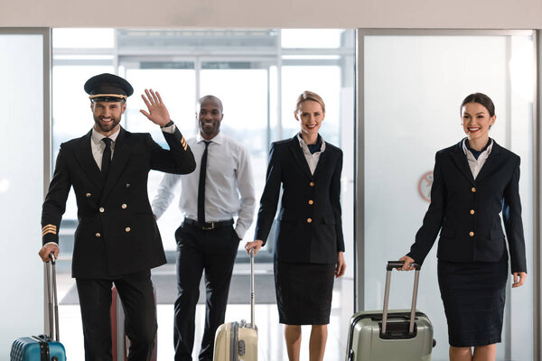 young aviation personnel team with suitcases at airport after flight