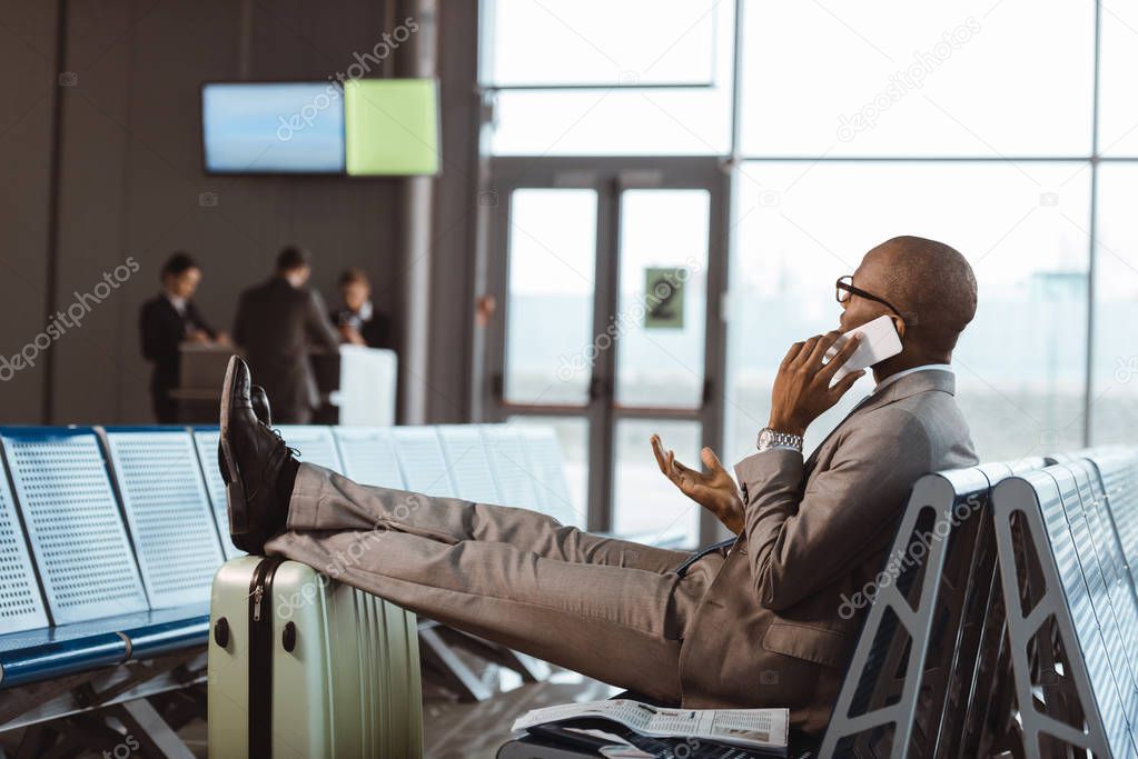 businessman talking by phone while waiting for flight at airport lobby