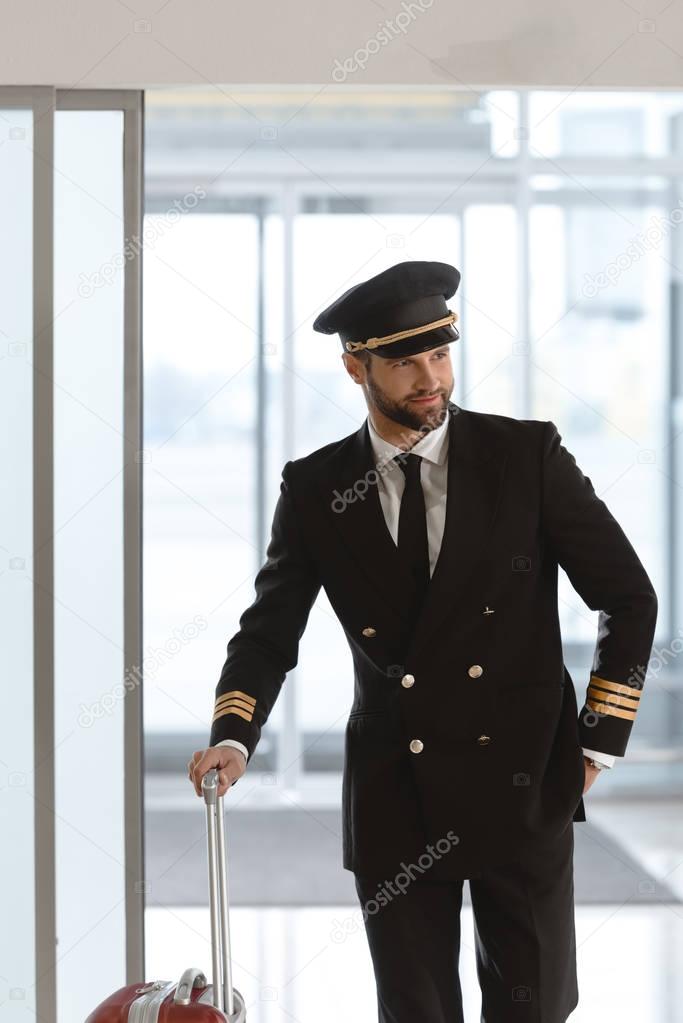 handsome young pilot with suitcase at departure area