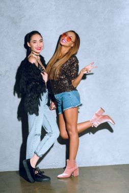 kameraya gülümseyen ve partide eğleniyor güzel moda çok ırklı kız görünümünü tam uzunlukta