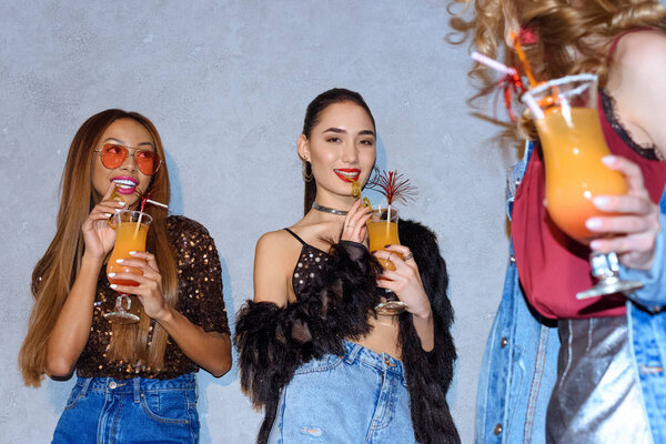 cropped shot of fashionable multiethnic women drinking cocktails at party