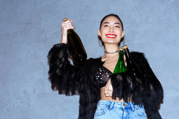 Fashionabla Glad Asiatisk Tjej Håller Flaskor Med Alkoholdrycker Grå — Stockfoto
