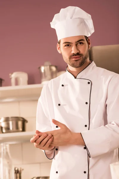 portrait of handsome confectioner in chef hat in restaurant kitchen