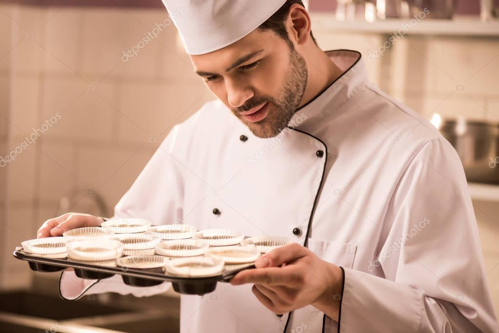 confectioner checking dough in baking forms in restaurant kitchen