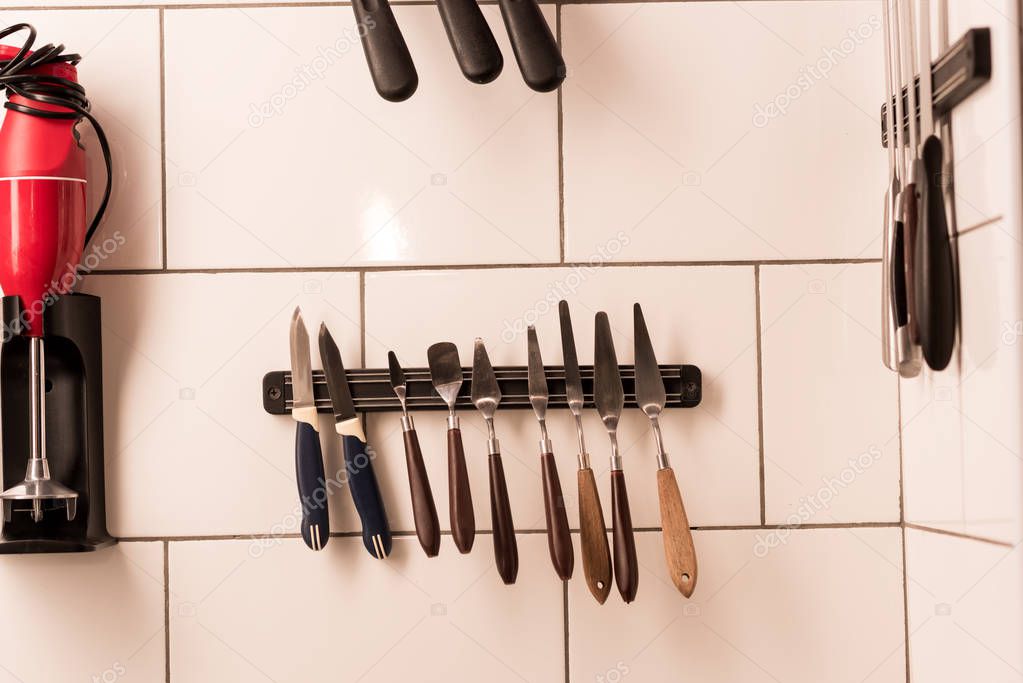 close up view of blender, arranged kitchen and bakery supplies hanging on wall