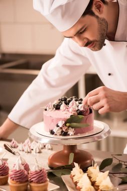 portrait of confectioner decorating cake in restaurant kitchen clipart