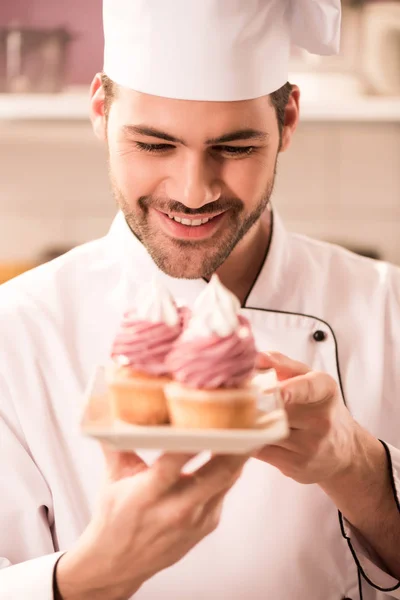 Ritratto Pasticciere Sorridente Che Guarda Cupcake Piatto Mano — Foto Stock