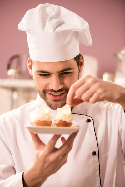 portrait of smiling confectioner decorating cupcakes in restaurant kitchen