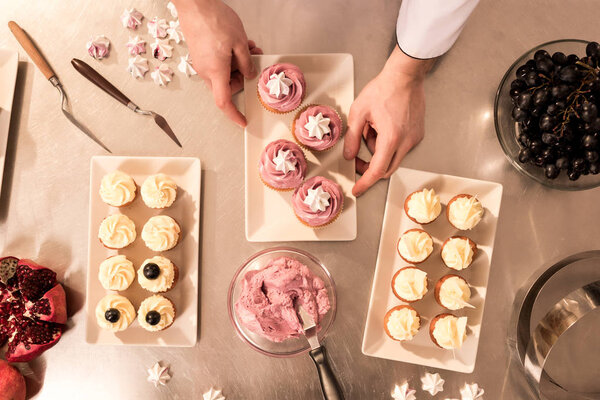 top view of confectioner arranging cupcakes on plate