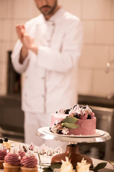 selective focus of cake, cupcakes and confectioner in restaurant kitchen