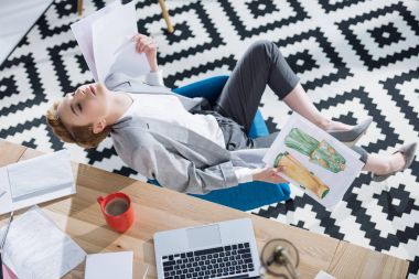 high angle view of exchausted fashion designer with sketches sitting at office clipart