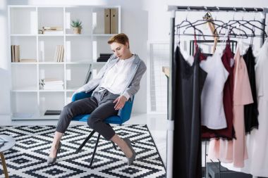 şık moda tasarımcısı modern ofisindeki sandalyede oturan
