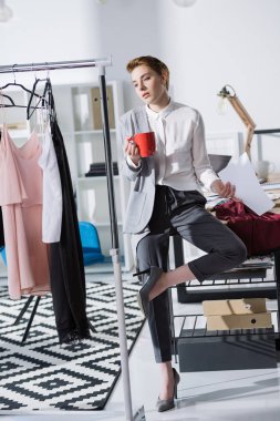 Ofis Masası ve bakarak oturan genç şık moda tasarımcısı gelinlik