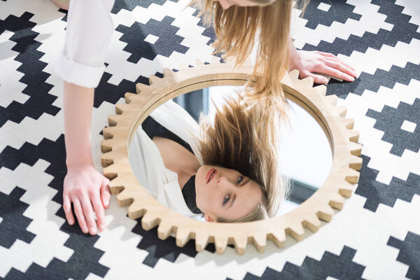 привлекательная молодая женщина смотрит в камеру через зеркальное отражение
