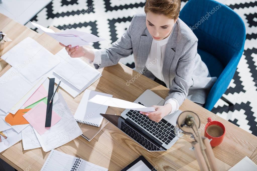 high angle view of stylish young businesswoman doing paperwork at office