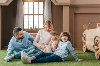 onların köpek yavrusu ile karton evin bahçesinde oturan genç aile