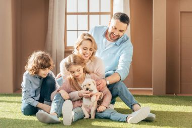 beautiful young family with yellow lab puppy on yard of cardboard house clipart