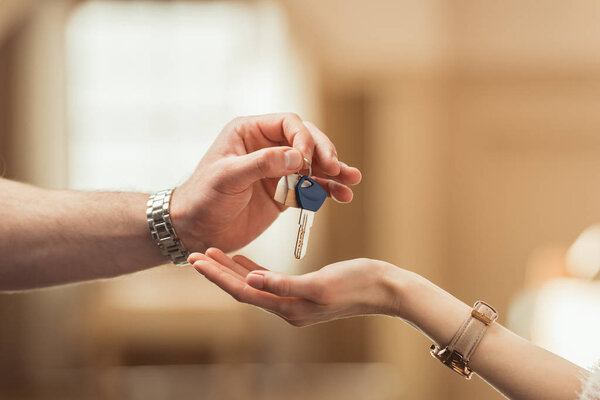 cropped shot of real estate agent passing key to client