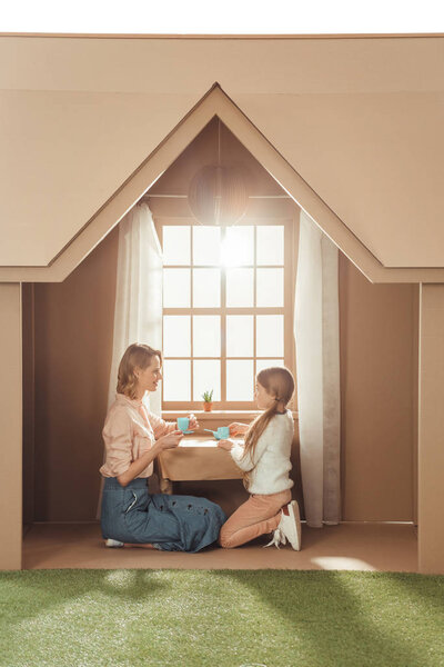 красивая мать и дочь чаепитие в картонном домике
