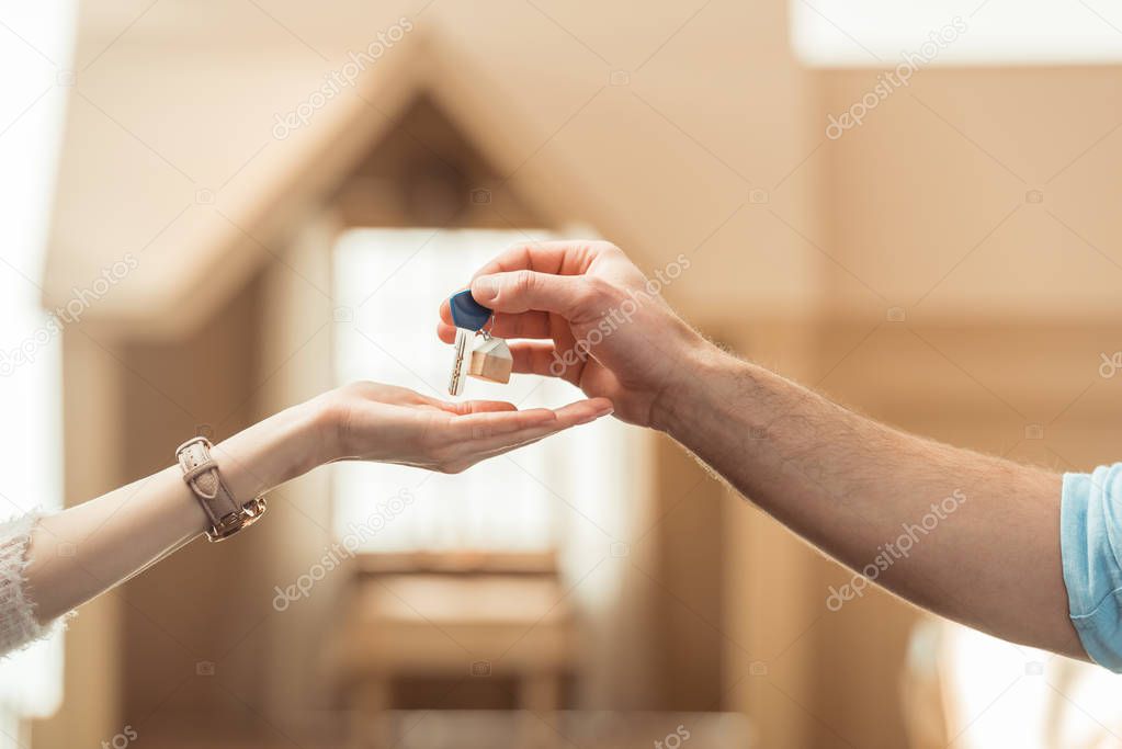 cropped shot of real estate agent passing key to client