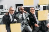 multikulturní usmívající se podnikatelé při pohledu na poznámky během setkání v kanceláři 
